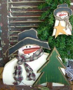 two snowmen with hats and scarfs are sitting in front of a christmas tree