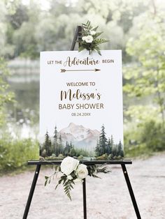 a welcome sign for a baby shower with flowers and greenery on the easel