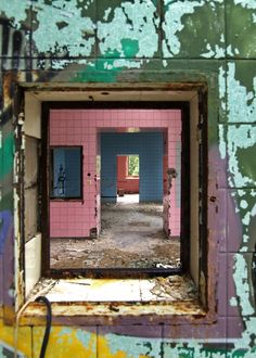 an open window in the middle of a room with colorful walls and peeling paint on it