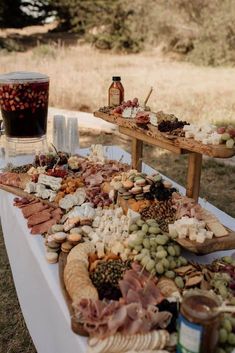 an assortment of cheeses, meats and other foods on a table with drinks