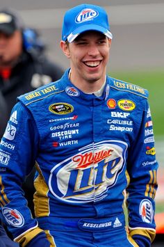 a man in a blue racing suit smiles at the camera