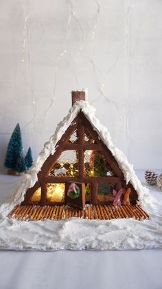 a small house made out of gingerbread with lights in the windows and snow on the roof