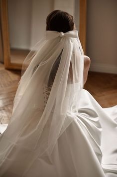 a woman in a wedding dress sitting on the floor with her veil over her head