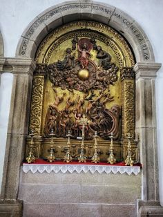 an ornate gold and red alter with candles on it's sides, in front of a white wall