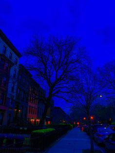 the street is lined with parked cars at night