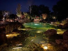 an outdoor pond at night with lights in the water