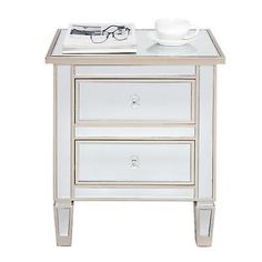 a white night stand with two drawers and a bowl on the top of it, next to a pair of glasses