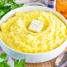 a white bowl filled with mashed potatoes on top of a wooden cutting board