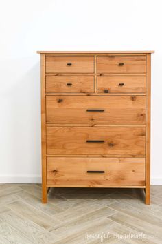 a wooden dresser sitting on top of a hard wood floor next to a white wall