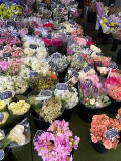 many different types of flowers on display at a flower shop with price tags attached to them