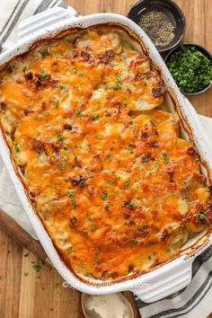 a casserole dish with cheese and meat in it on a wooden table next to other dishes