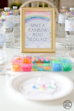 there is a sign that says make a rainbow bead necklace next to some water bottles