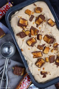 a pan filled with ice cream topped with chocolate and marshmallows next to candy bars