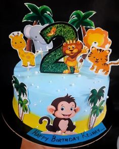 a blue birthday cake with animals on it and the number two candle in the middle