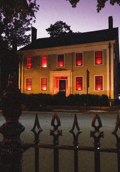 a large white house with red lights on it's windows and fenced in area