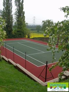 a tennis court surrounded by trees and grass