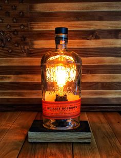 a bottle of whiskey sitting on top of a wooden table next to a light bulb