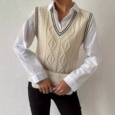 a woman in white shirt and black pants standing with her hands on her hips wearing a sweater vest