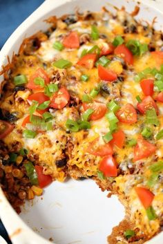 a casserole dish with cheese, tomatoes and green onions on it's side