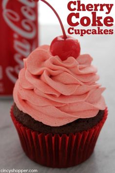 a cupcake with pink frosting and a cherry on top is in front of a coca - cola can