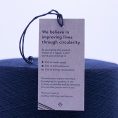 a blue ball of yarn with a tag stating we believe in improvements through circularity