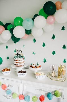 a party with balloons, cake and desserts on a dresser in front of the wall