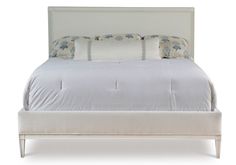 a bed with white linens and pillows on it's headboard, in front of a white background