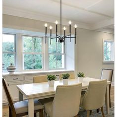 a dining room table with six chairs and a chandelier hanging from the ceiling