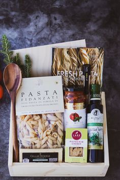 an assortment of pasta and wine in a wooden box