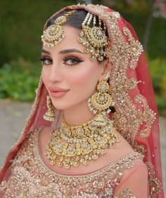 a woman in a bridal outfit with jewelry on her head and veil over her face