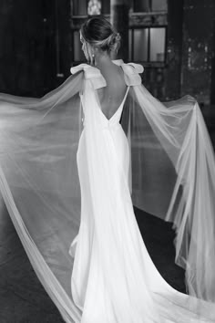 black and white photo of woman in wedding dress with veil over her shoulder, back view