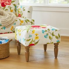 a living room with a flowered chair and footstool on the floor next to a basket