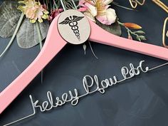 a pink wooden hanger with the words kelsey plu lab on it