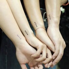 three people holding hands with small tattoos on them