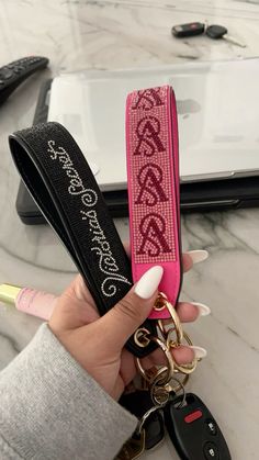 a person holding a pink keychain with the word love on it and two keys attached to it