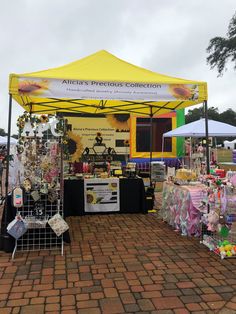 a yellow tent with sunflowers and other items on display at an outdoor market