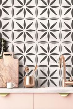 a kitchen with pink cabinets and black and white tiles on the wall, along with copper faucets