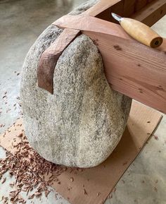 a large rock with a knife sticking out of it next to a piece of wood