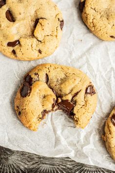 chocolate chip cookies on parchment paper with one broken in half and the other partially eaten