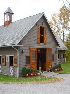 a small gray house with orange shutters and a clock tower on the top of it