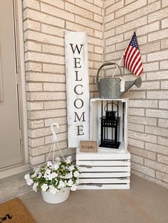 a welcome sign next to a potted plant on the front porch with an american flag