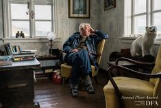 an old man sitting in a chair next to a white dog on the other side