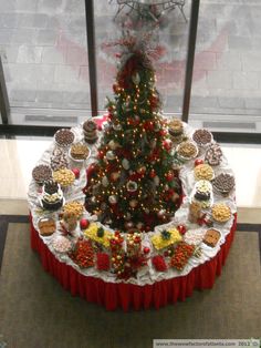 a decorated christmas tree in the center of a table with cupcakes on it