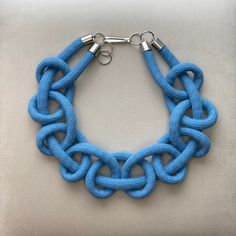 a blue bracelet with two silver clasps on a gray surface and one is made out of rope