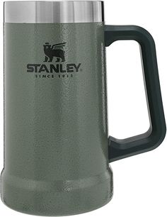 the stanley travel mug is green and has a black handle, with an emblem on it