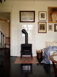 a black stove sitting in the middle of a living room next to a wall with pictures on it