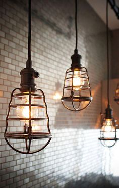 three light fixtures hanging from a brick wall