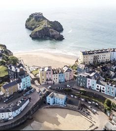 an aerial view of some buildings near the beach and water with a rock outcropping in the distance