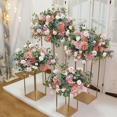 pink and white flowers are arranged on gold stands