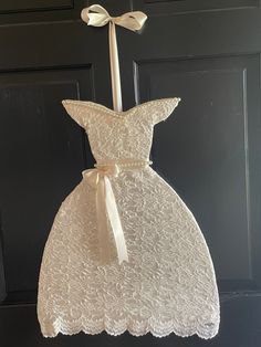 a white dress hanging from the side of a door with a bow on it's back